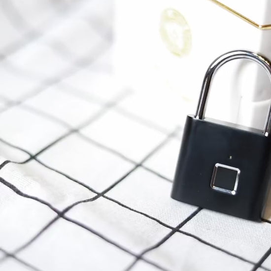 Smart fingerprint padlock in hand — black and silver, showing the fingerprint sensor and steel shackle